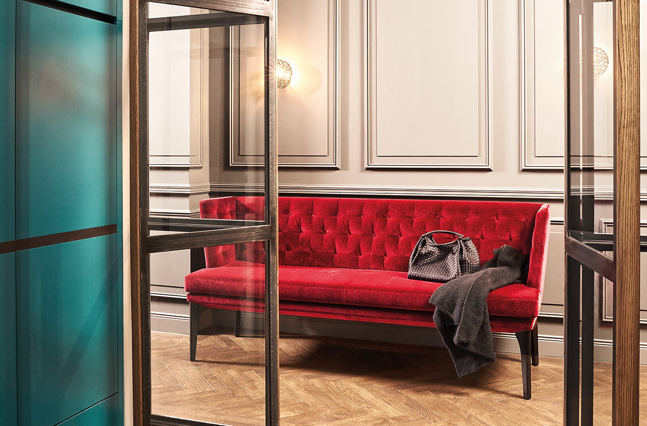 Elegante Sitzbank mit rotem Samtbezug und Knopfheftung in einem klassischen Raum.